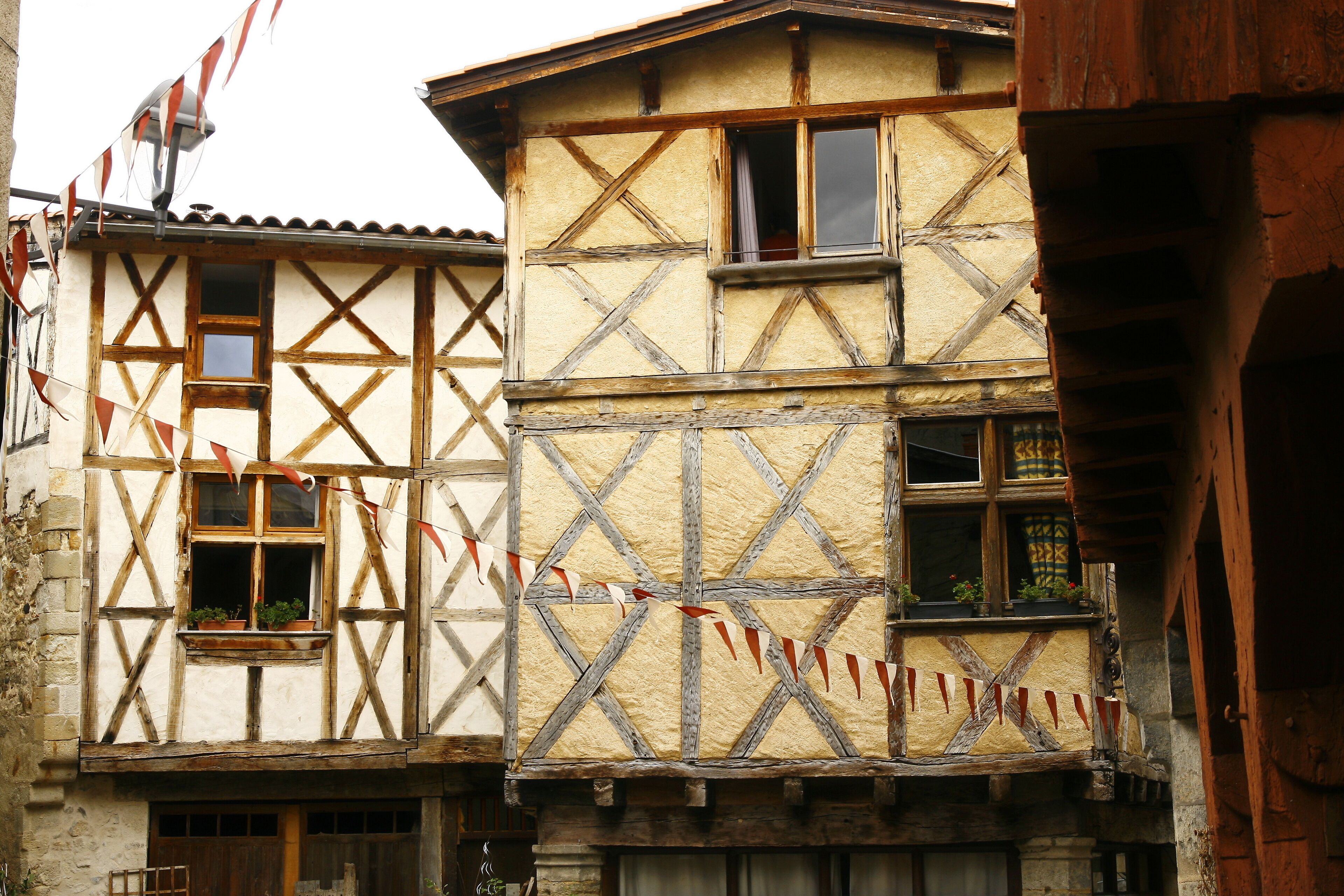 A traditional half-timbered building with a sloped roof and red and white flags.