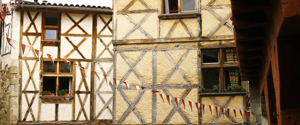 A traditional half-timbered building with a sloped roof and red and white flags.