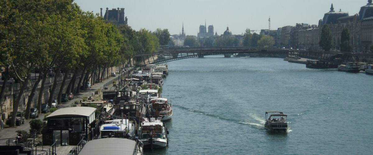 A river with boats, a bridge, and buildings in the background.