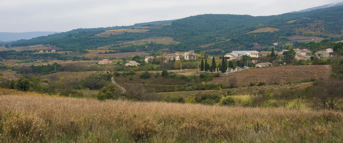 A rural landscape with rolling hills, scattered houses, and a prominent church with a bell tower.