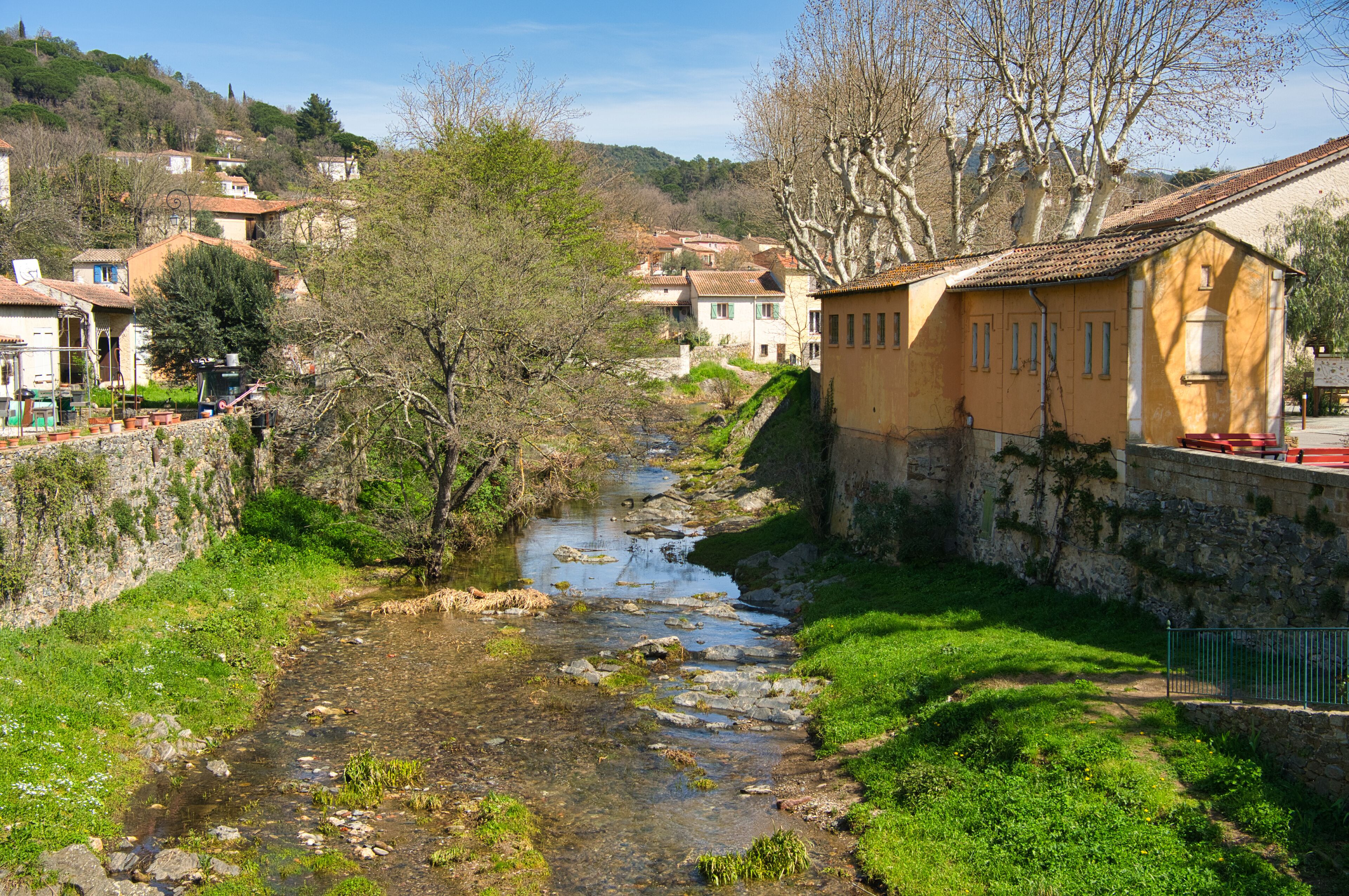 A river flowing through a village with houses on the hillside.