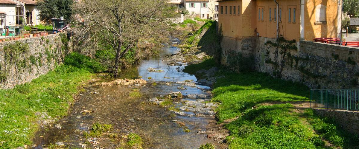 A river flowing through a village with houses on the hillside.