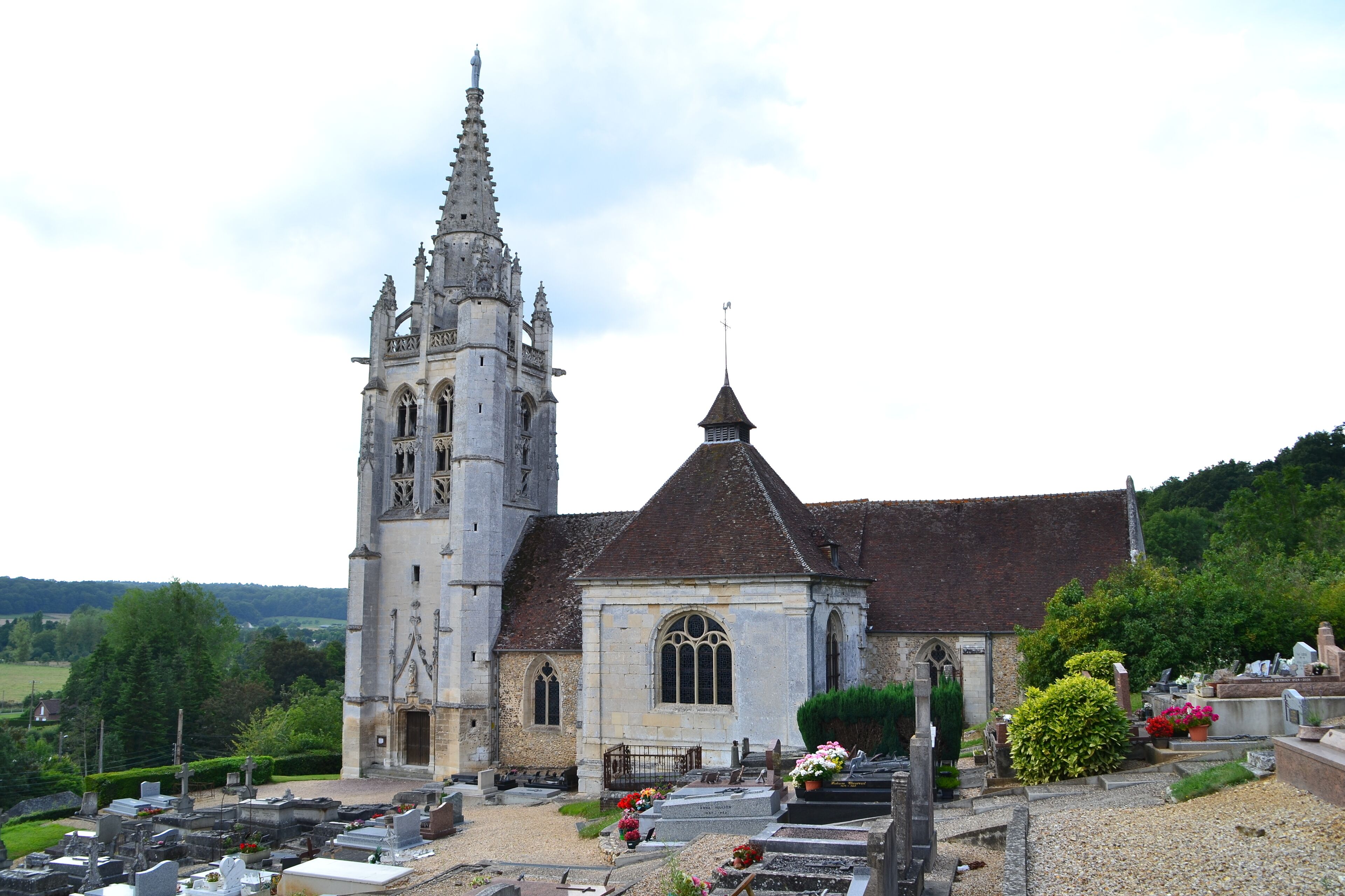A church with a tall bell tower and a smaller building with a pointed roof.
