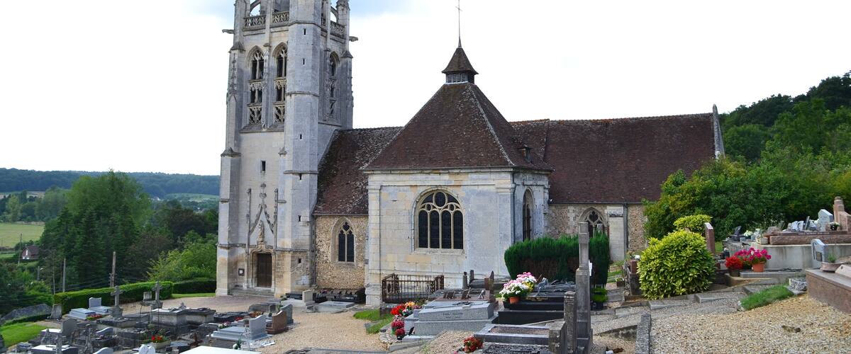A church with a tall bell tower and a smaller building with a pointed roof.
