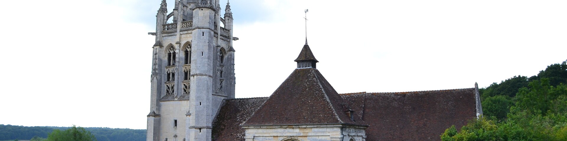 A church with a tall bell tower and a smaller building with a pointed roof.