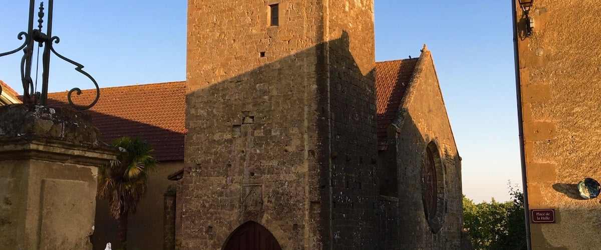 A historic church with a bell tower, a yellow convertible parked in front, and a weather vane.