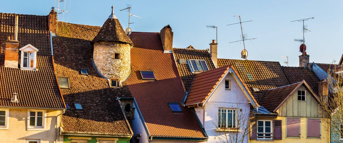 A row of traditional European buildings with sloped roofs and multiple antennas.