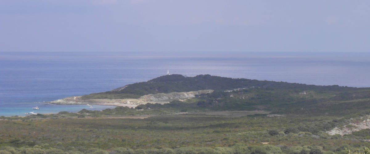 A coastal landscape with a lighthouse on a hill, a beach, and the sea.