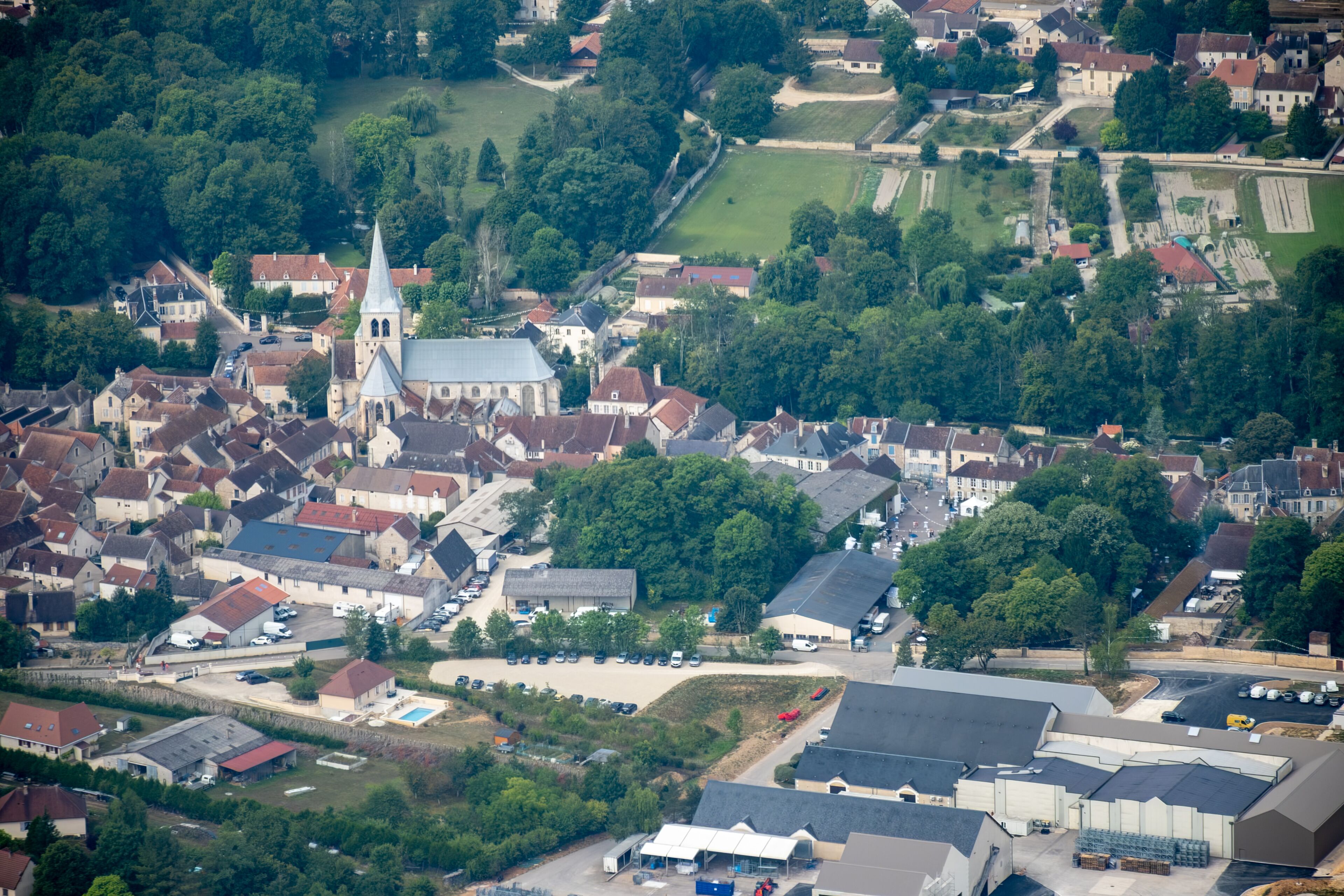 An aerial view of a town with a prominent church, residential houses, and a large industrial area.