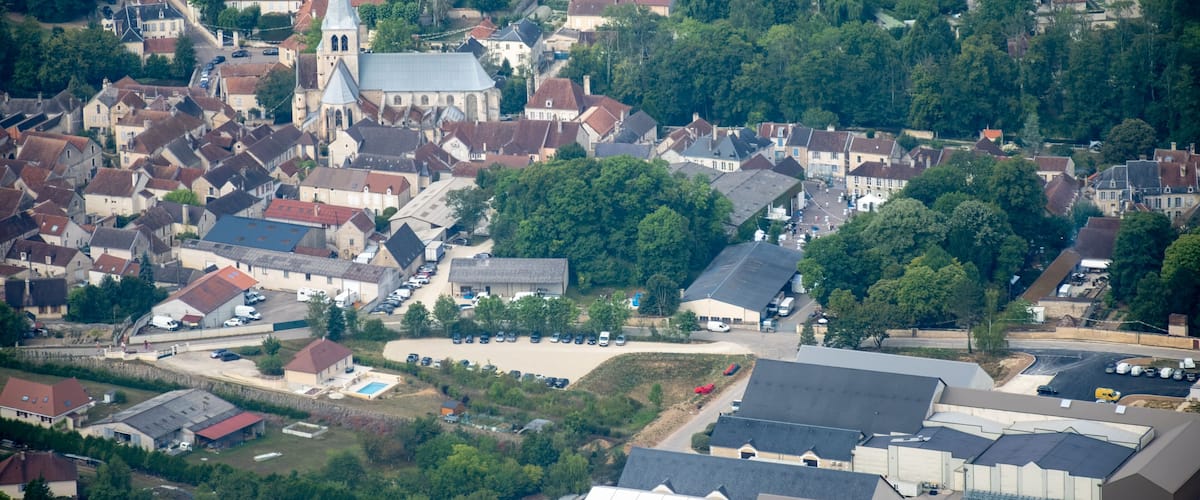 An aerial view of a town with a prominent church, residential houses, and a large industrial area.