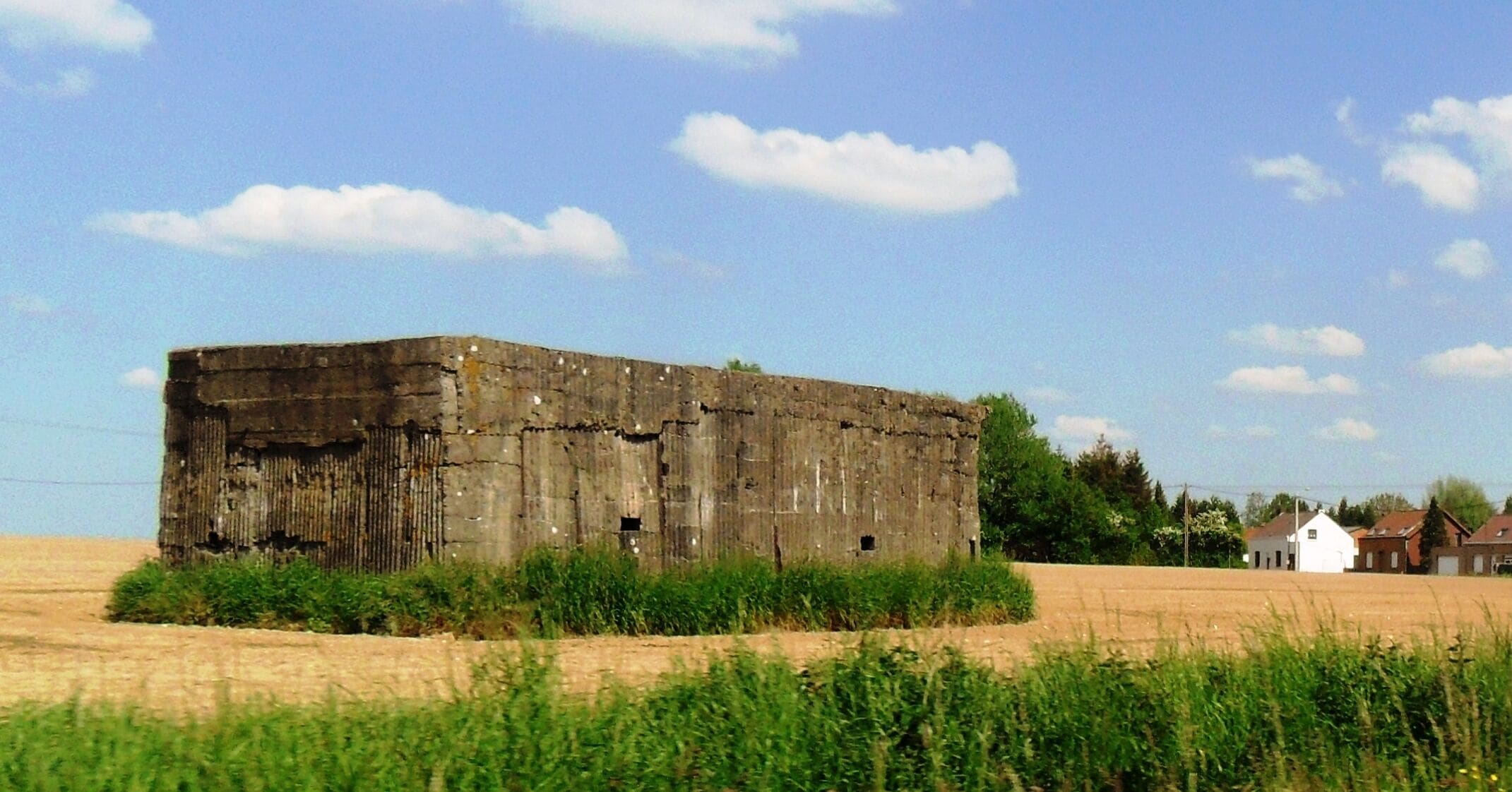 A large, weathered barn in a field with a clear sky.