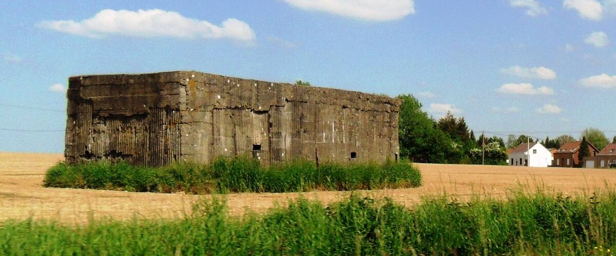 A large, weathered barn in a field with a clear sky.