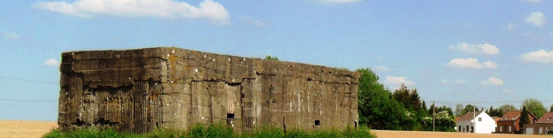 A large, weathered barn in a field with a clear sky.