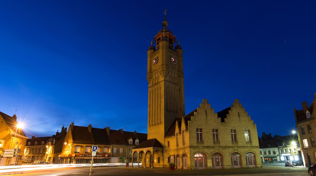 A historic clock tower at twilight with illuminated windows and a clear sky.