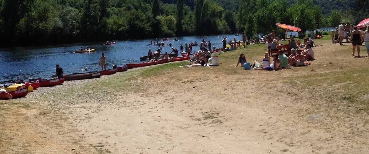 A lakeside scene with people swimming and sunbathing.