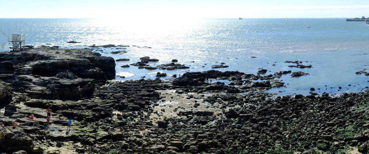 A rocky coastline with fishing structures and boats on the water.