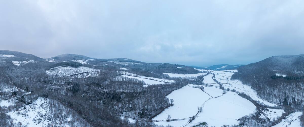 A snow-covered mountain landscape with valleys and forests.