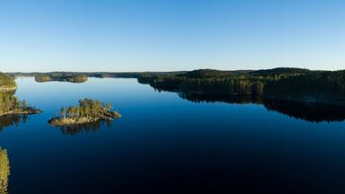 Un lac paisible, entouré de forêts denses, et une petite île couverte d’arbres.