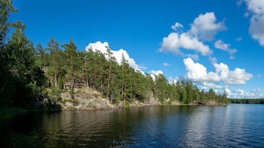 Tyyni järvi, jonka ympärillä on tiheää metsää ja jyrkkiä kallioita, ja yllä kirkas, sininen taivas.
