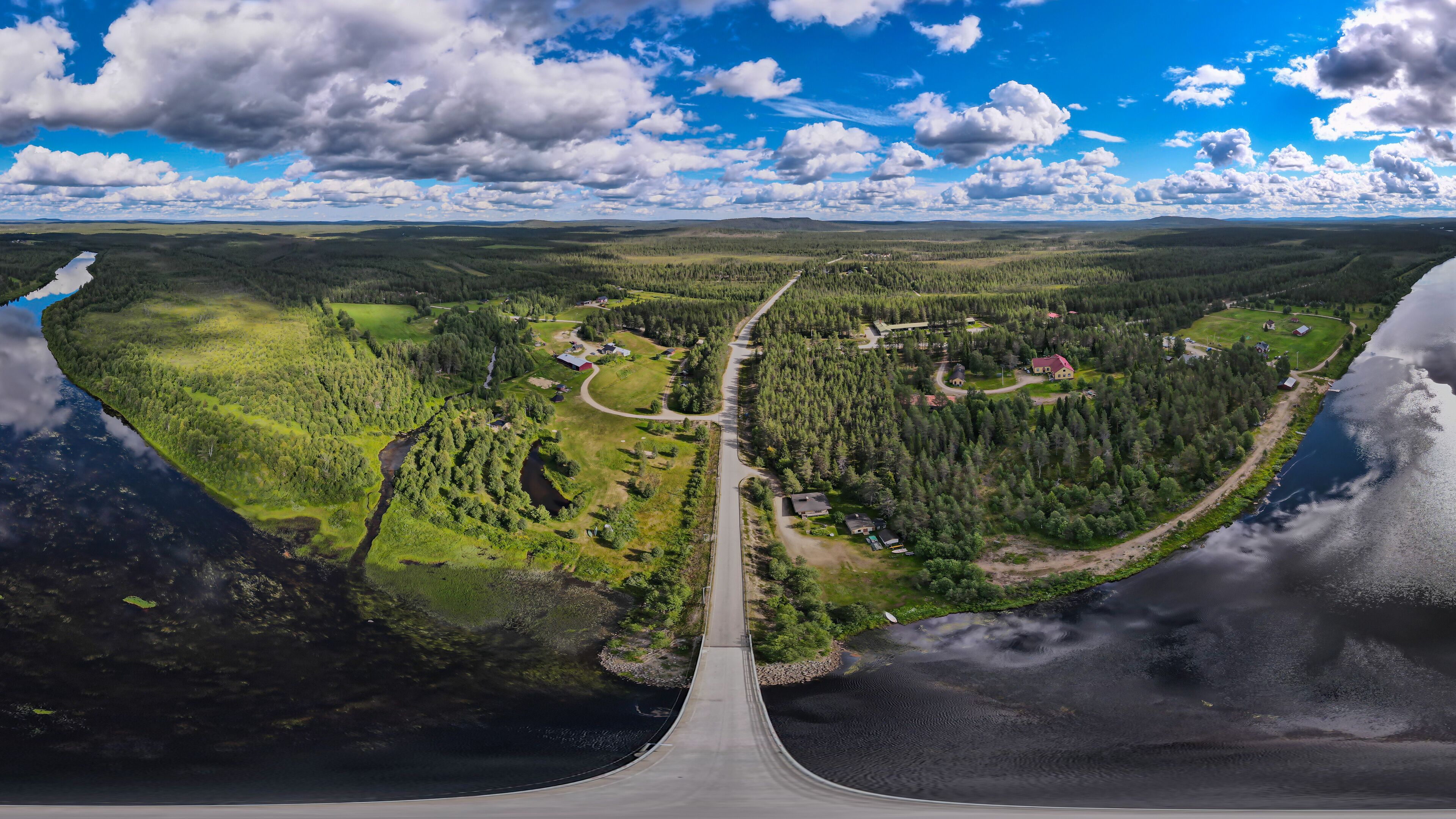 An aerial view of a coastal road with a river on one side and a forested area on the other.