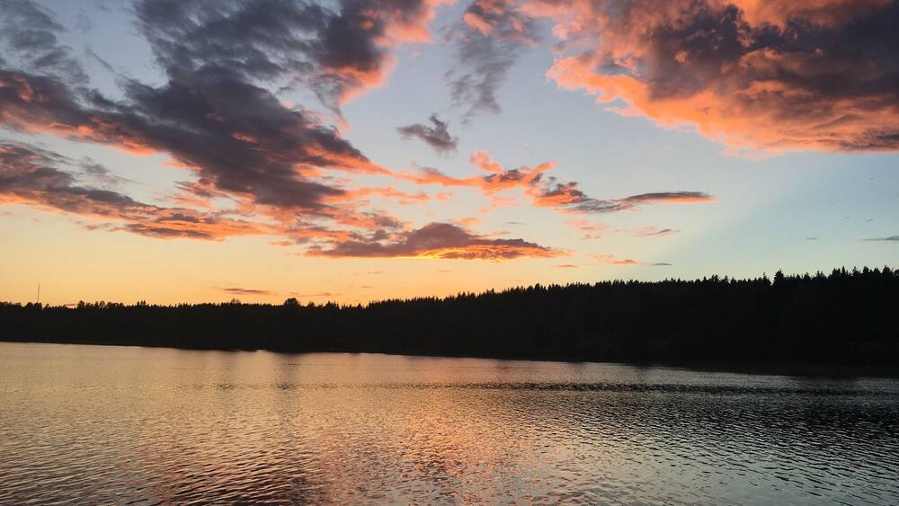 A sunset over a calm lake with a forested shoreline.