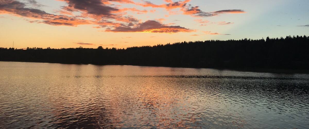 A sunset over a calm lake with a forested shoreline.