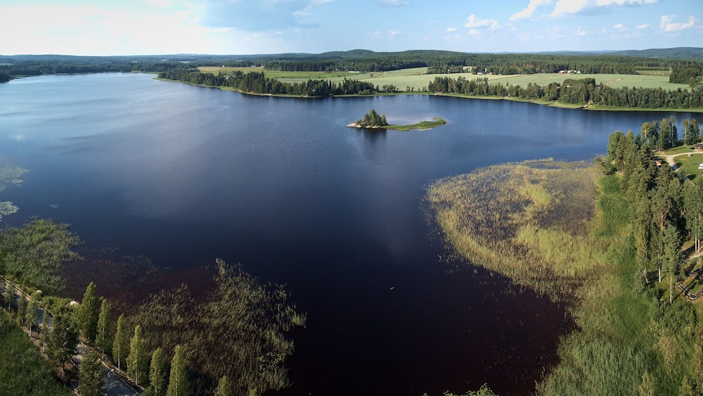 Aerial view of blue lake and green forests on a sunny summer day. Bird's eye view drone photography. Ruovesi, Finland.