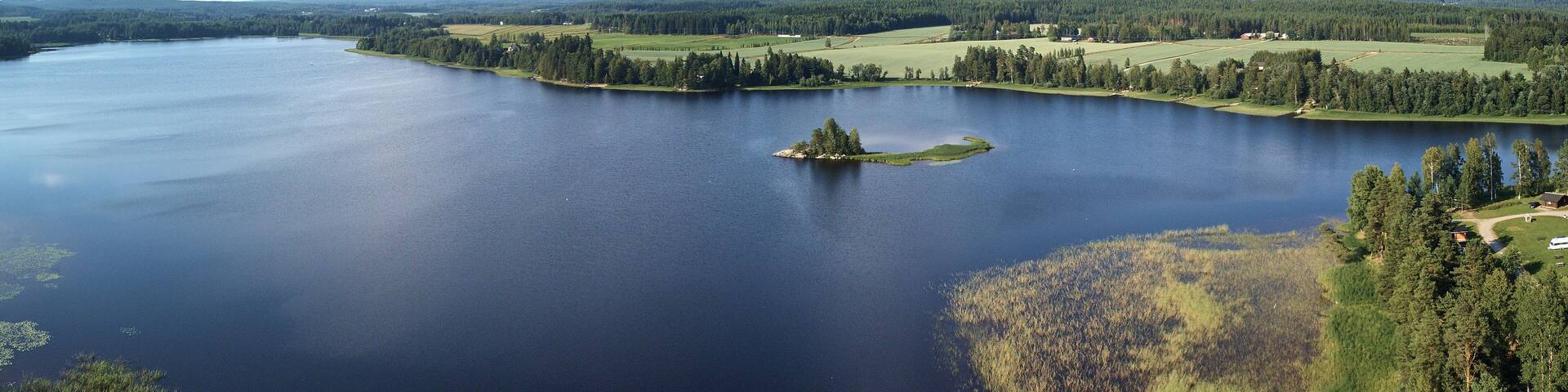 Aerial view of blue lake and green forests on a sunny summer day. Bird's eye view drone photography. Ruovesi, Finland.