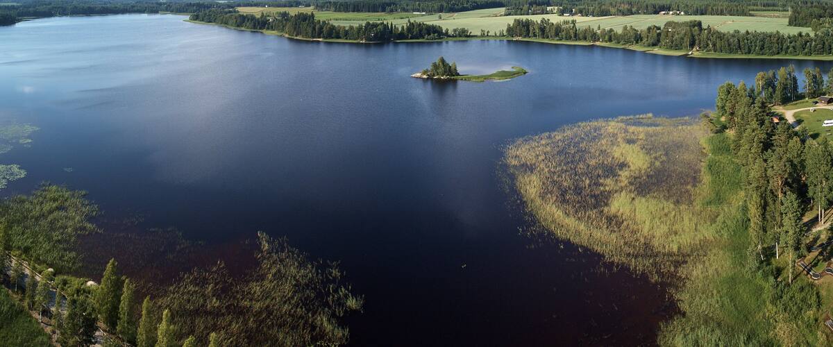 A large lake surrounded by forested areas and fields.