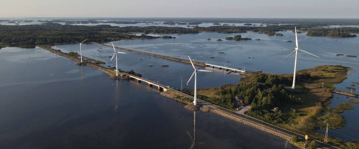 A coastal area with wind turbines and a bridge over water.