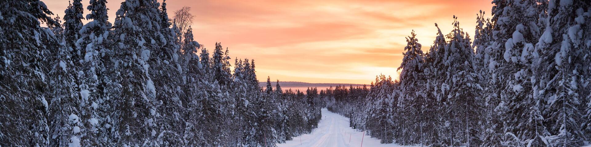 Icy snow covered winter road in the Arctic Circle at sunset in Lapland, Finland