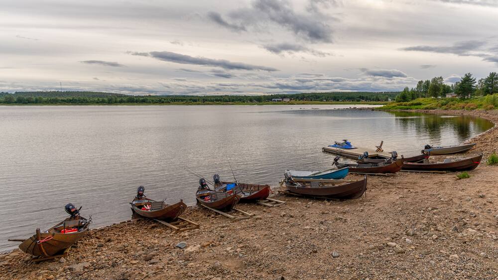 panorama view of many wooden motorboats used for salmon fishing on the banks of the Tornionjoki River in Finnish Lapland