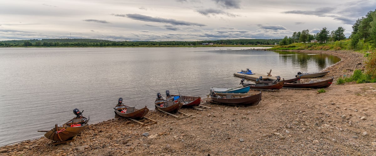 A lakeside with several boats moored on a rocky shore.