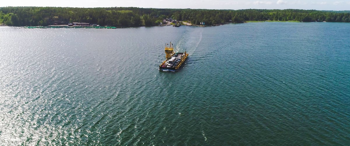 A cargo ship on a calm lake with a forested shoreline.