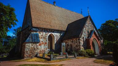 A stone church with a tiled roof and arched windows.