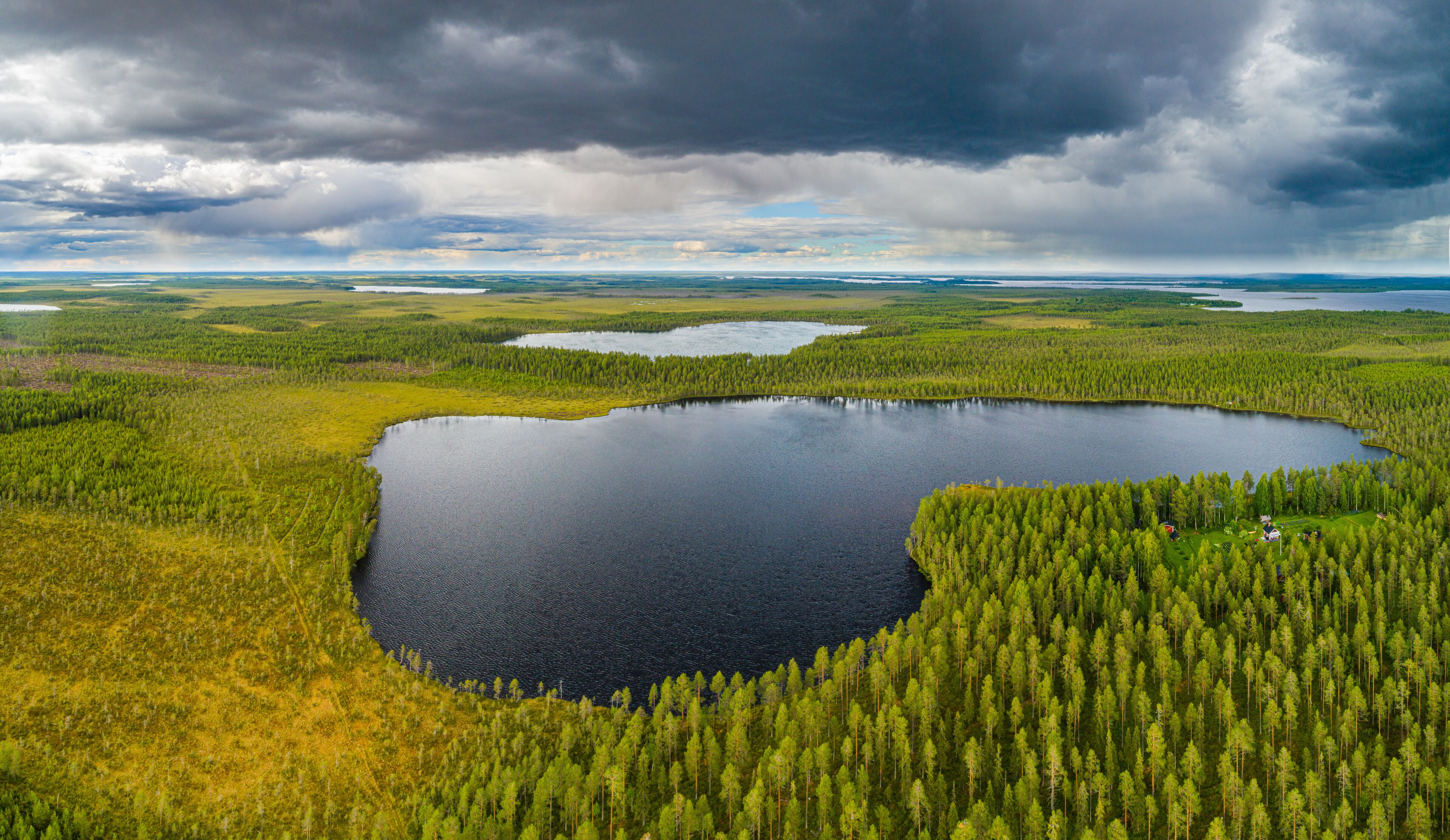 A large lake surrounded by dense forests and a cloudy sky.