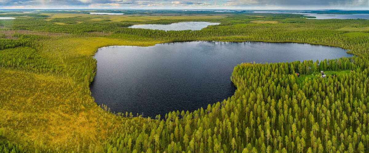 A large lake surrounded by dense forests and a cloudy sky.
