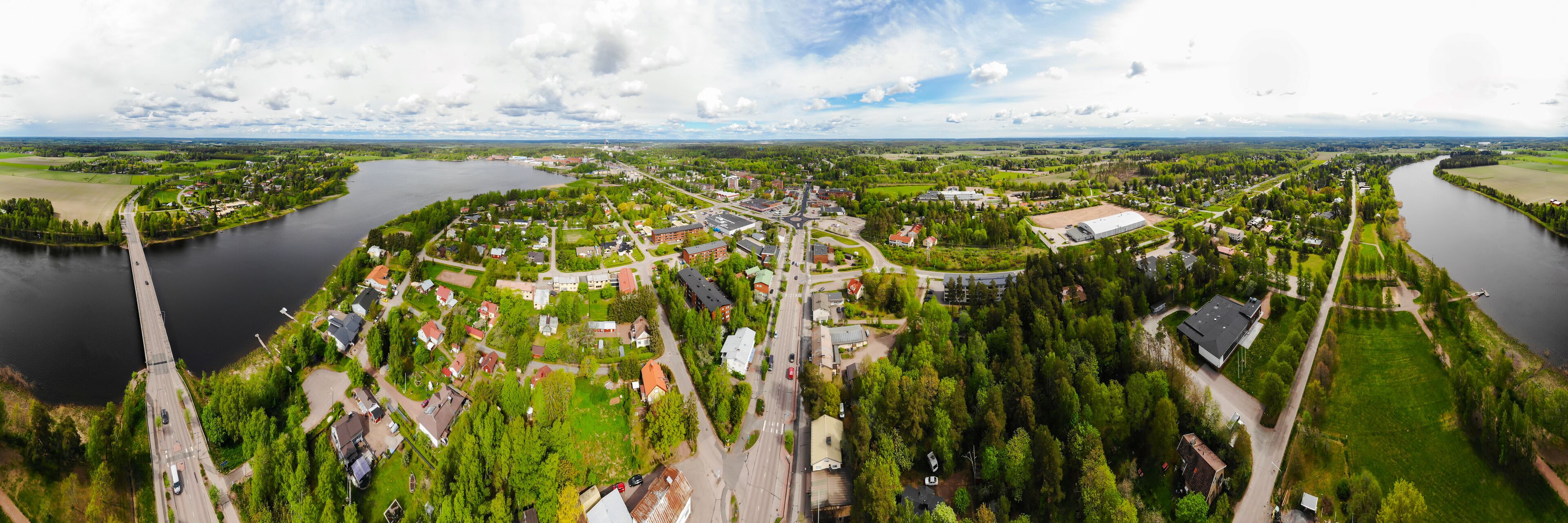 An aerial view of a town with a river, green fields, and residential areas.