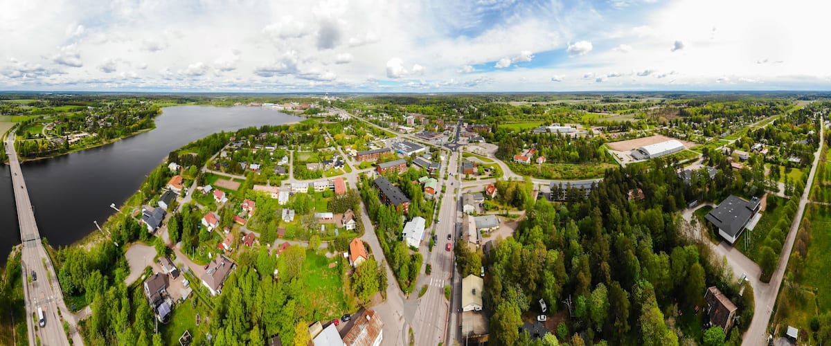 An aerial view of a town with a river, green fields, and residential areas.