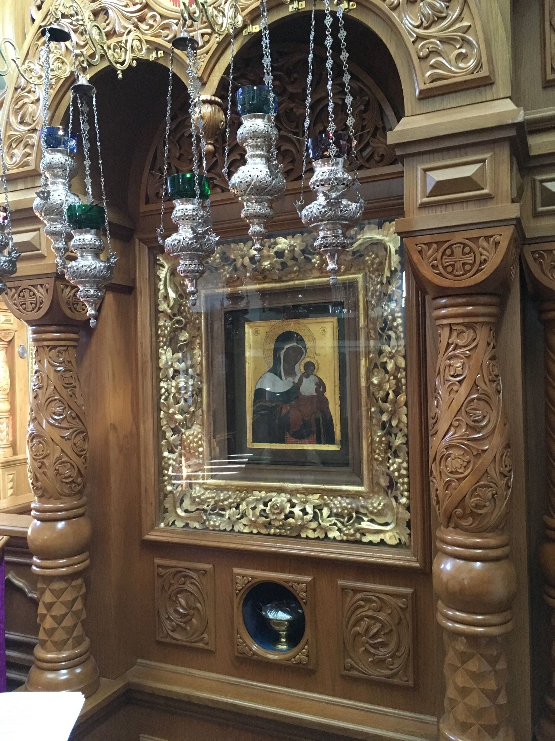 An ornate wooden structure with intricate carvings and a framed religious icon.