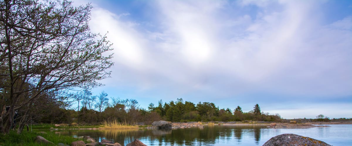 A calm lake with large rocks and trees along the shore.