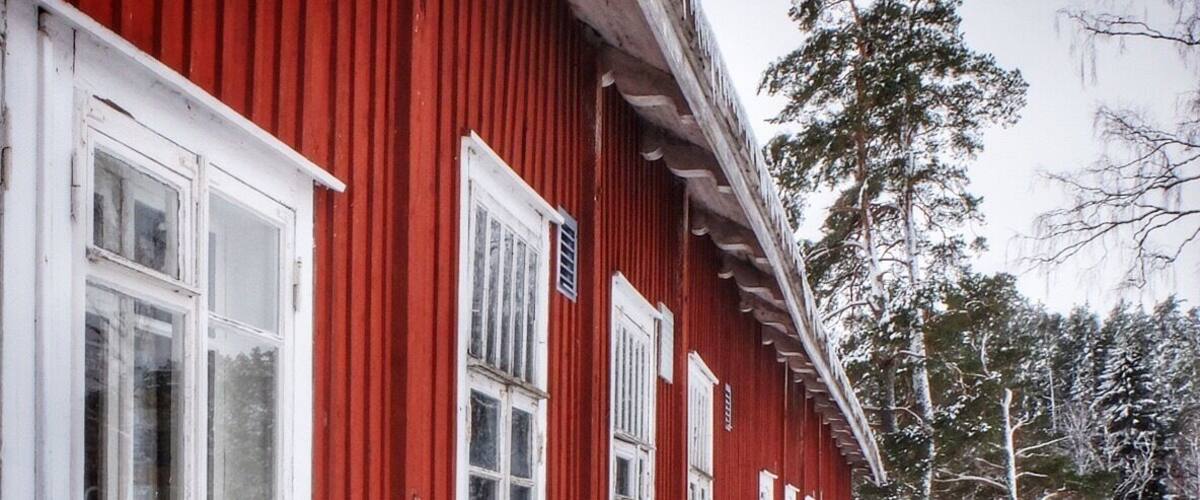 A red wooden building with white windows and a snow-covered ground.