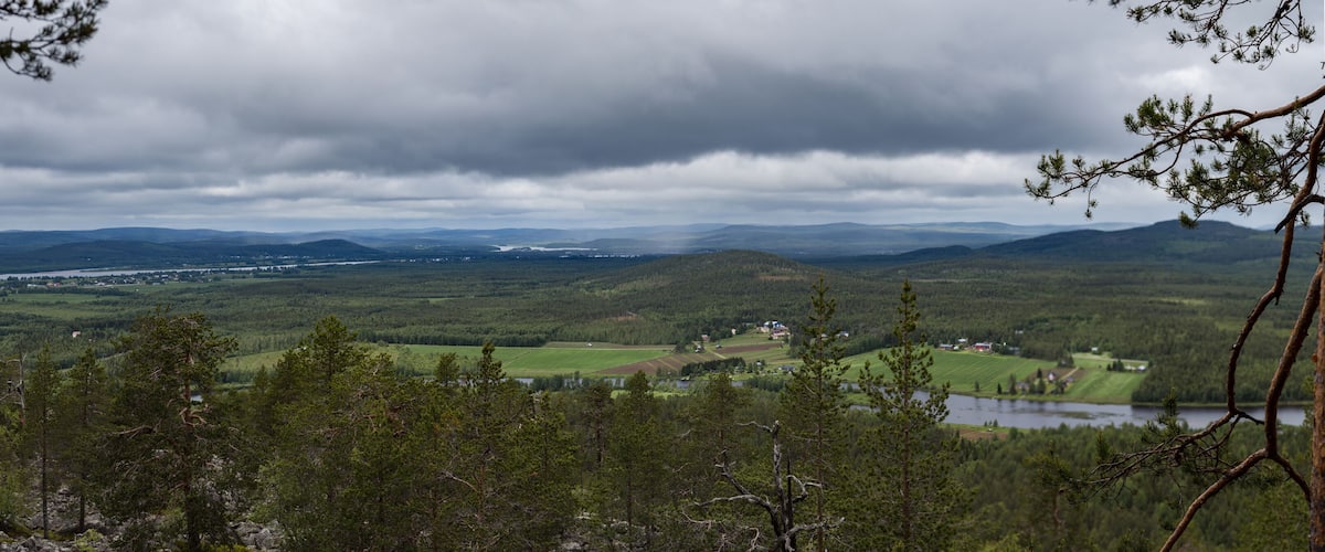 A mountainous landscape with a river, forested areas, and distant hills.
