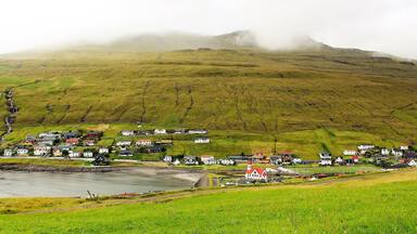 An idyllic, misty view of Sandavágur! I was on my way to the otherworldly Trøllkonufingur! Trøllkonufingur was one of the best sights on Vágar Island and one of the highlights of my trip. But, I also enjoyed the walk to and from there! I hiked about 12 KM that entire day and it was well worth it.
Sandavágur has been voted the most well-kept village in the Faroes twice. And it's the most famous "city" in the country, and best voted traveling experience. Although, not an actual city at all - the population is only around 861! The name Sandavágur means sandy bay and refers to the sandy beach which used to be much larger than present. From one point in Sandavágur you can get a view of all the southern islands in the Faroes. And the red-roofed church seen in this photo is one of the best in the Faroe Islands! In fact, members of the Danish Royal Family were there 1 day after I was! I even saw their motorcade as they were continuing on their journey. A pretty cool experience, too ;).
I took this photo on August 25th.