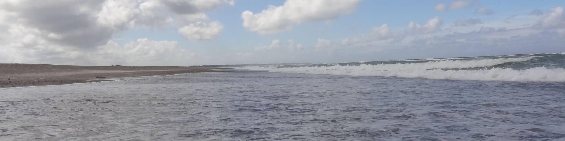 Deserted beach with clear water, waves and clouds near Klim in Denmark