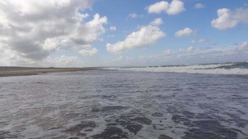 Deserted beach with clear water, waves and clouds near Klim in Denmark