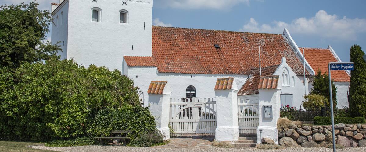 A white church with a red-tiled roof and a bell tower.