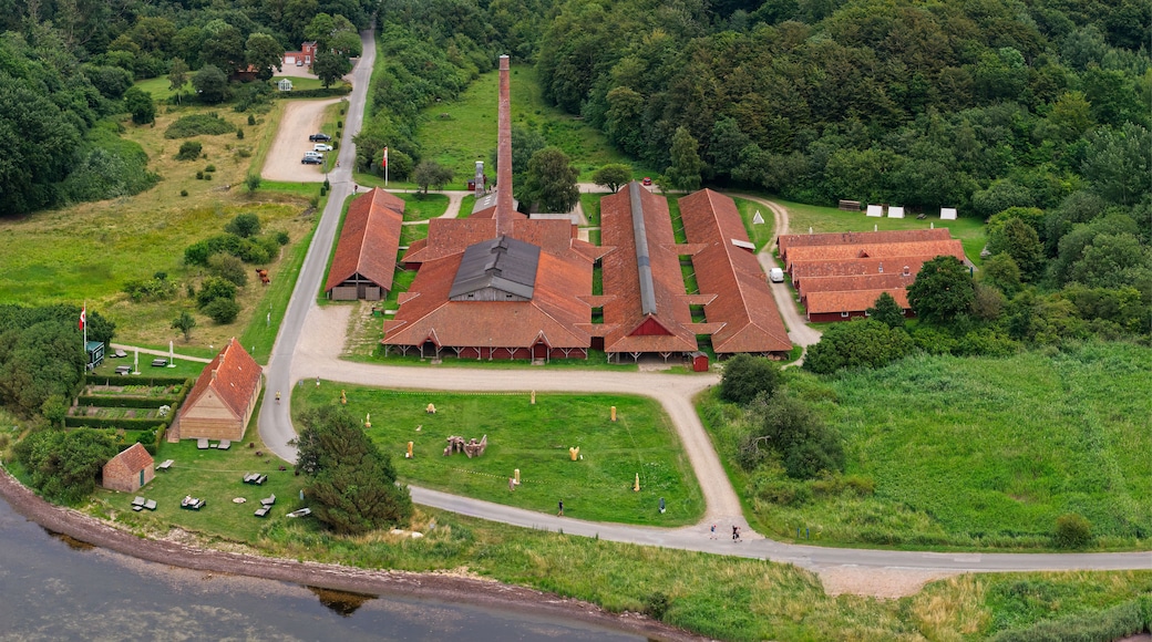 An aerial view of a rural area with a large brick building, a church, and a river.