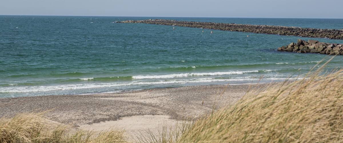 A beach with pebbles, waves, and a rocky breakwater.