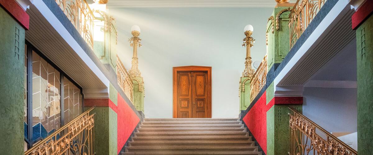 A grand staircase with ornate railings and a wooden door at the top.